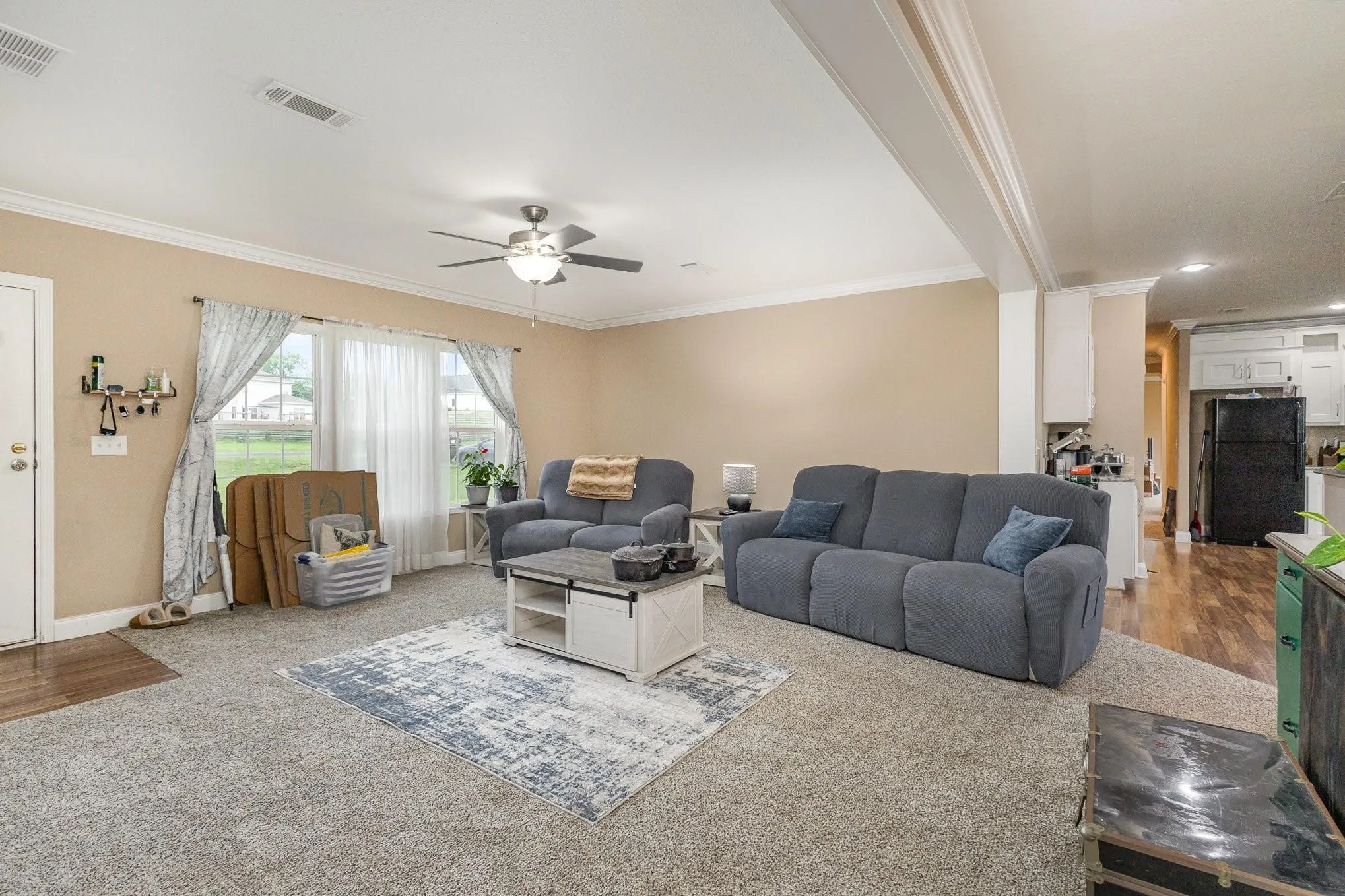 Living area featuring textured carpeting, neutral wall tones, and crown molding