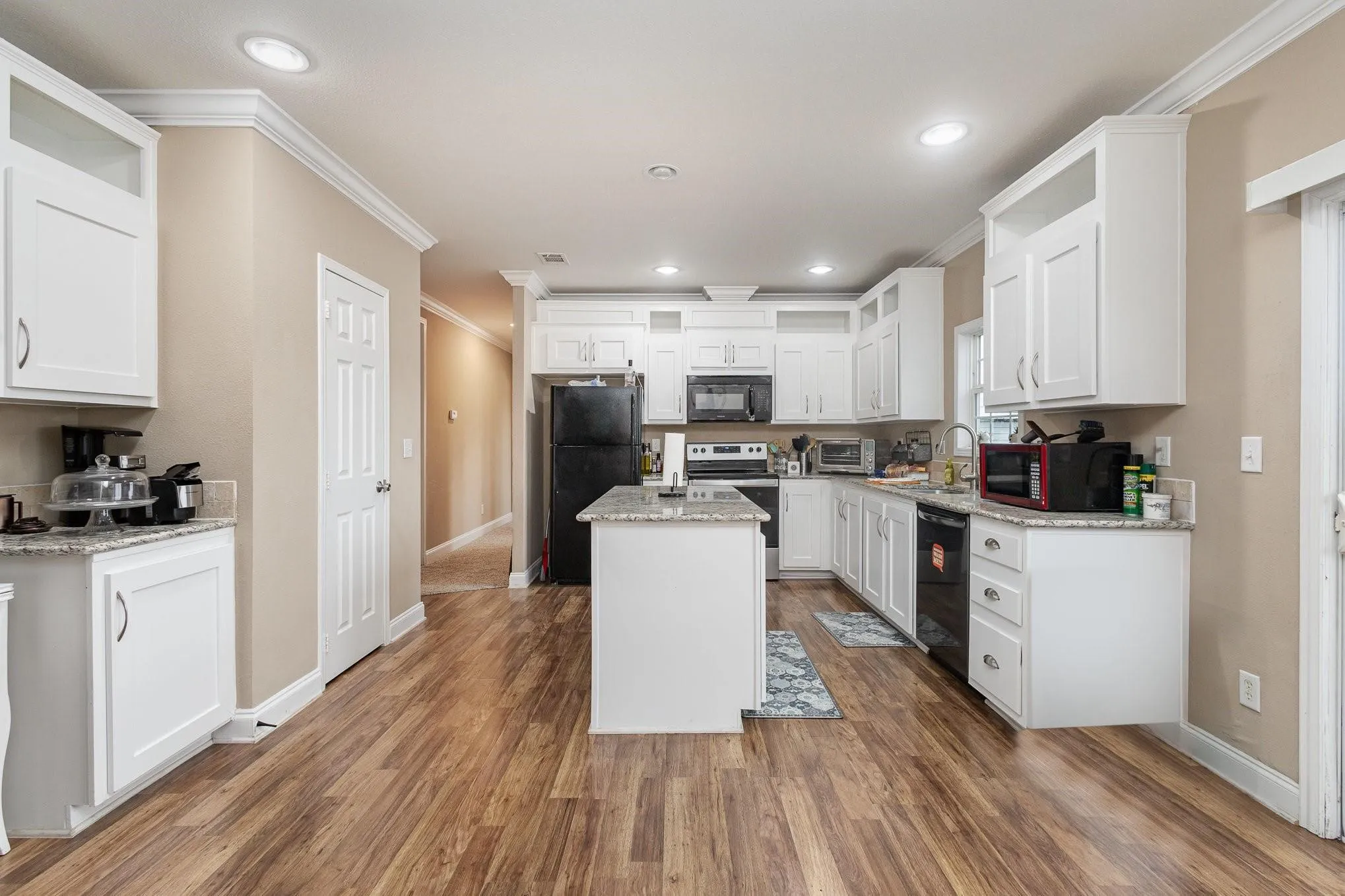 Kitchen featuring white cabinetry, wood-finish flooring, a central island with granite-style countertop, recessed lighting, and black appliances