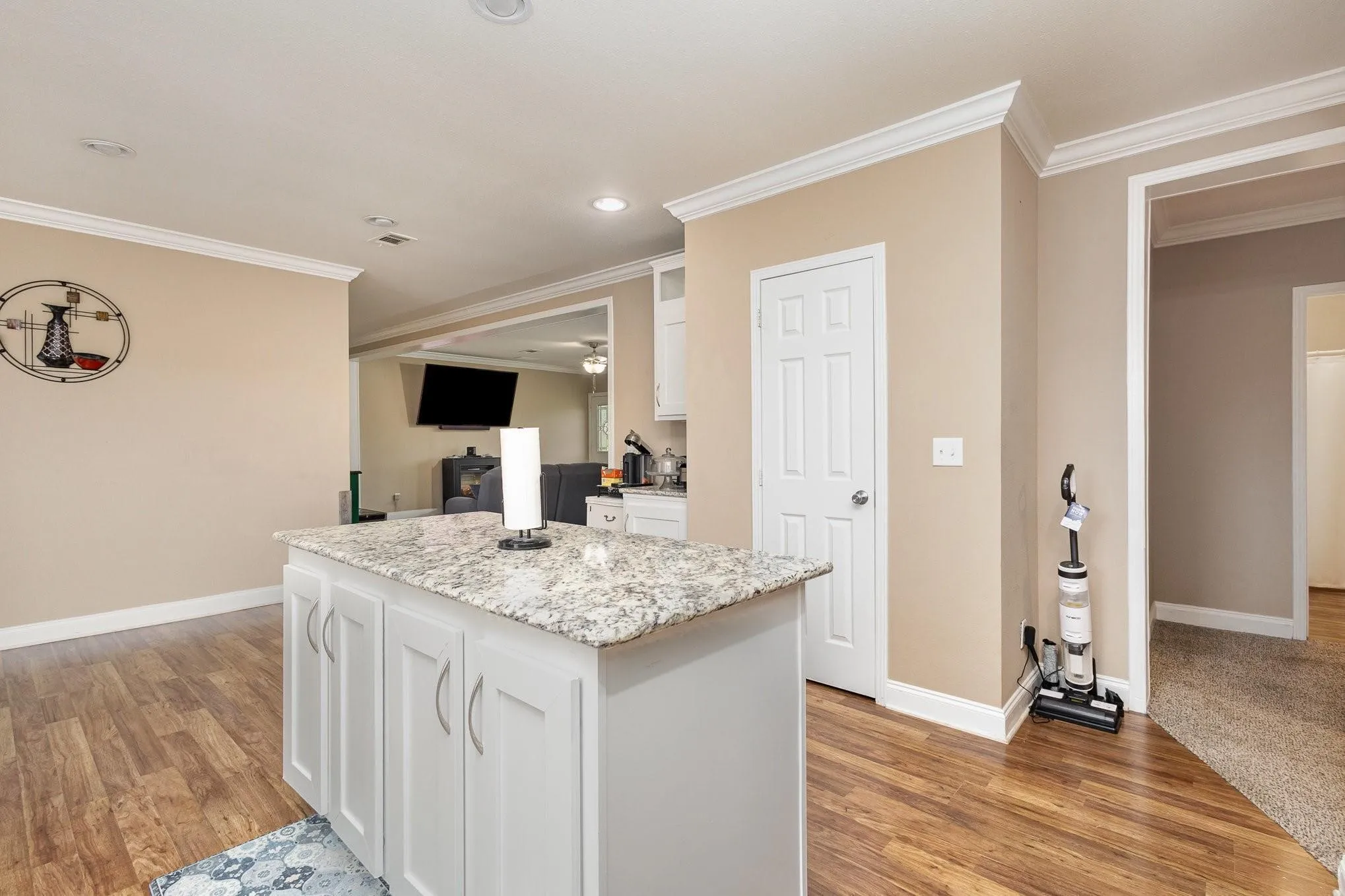 Kitchen island featuring white shaker-style cabinetry and a speckled stone countertop