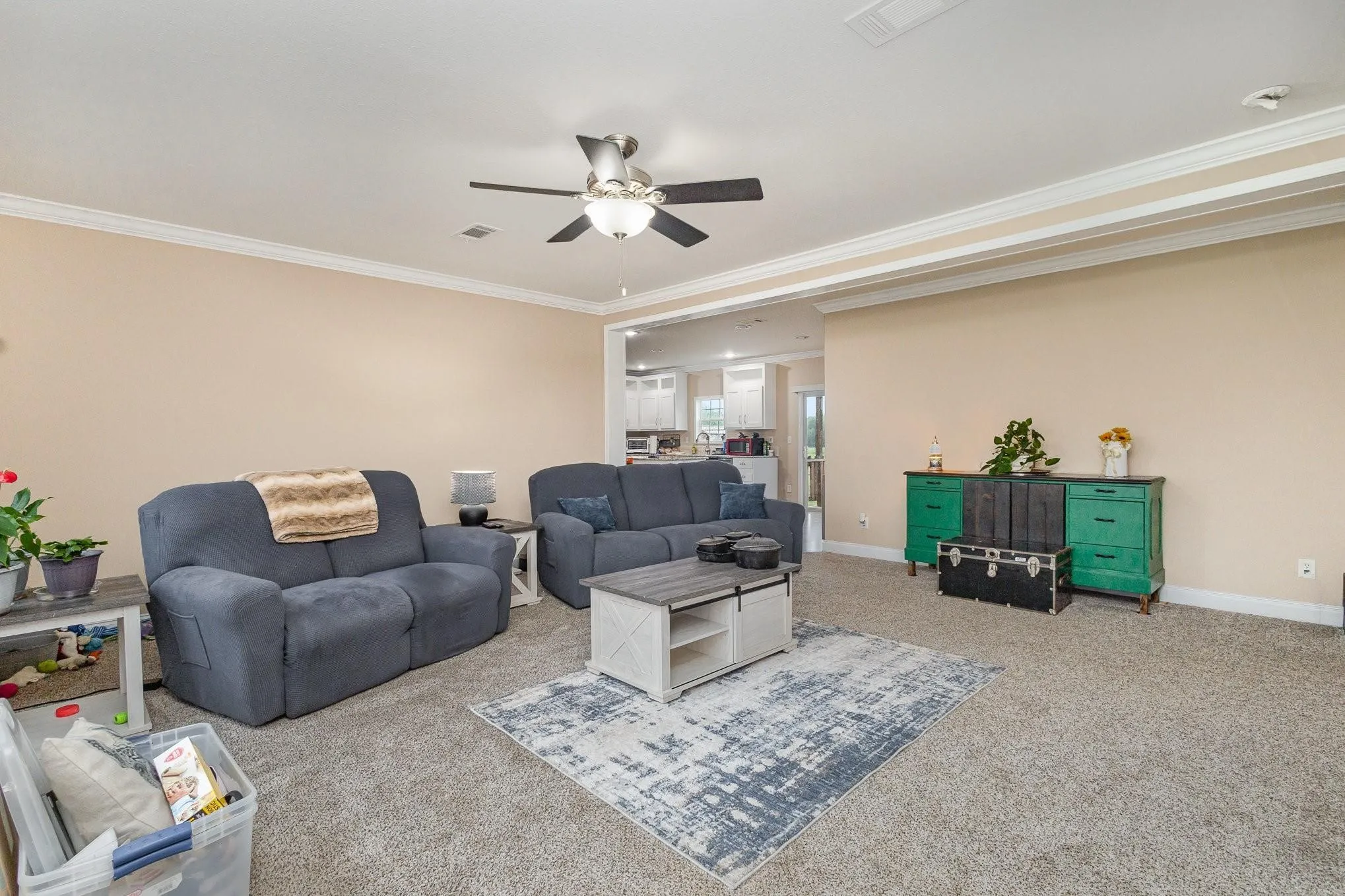 Spacious living area featuring neutral-toned walls, crown molding, and plush carpeting