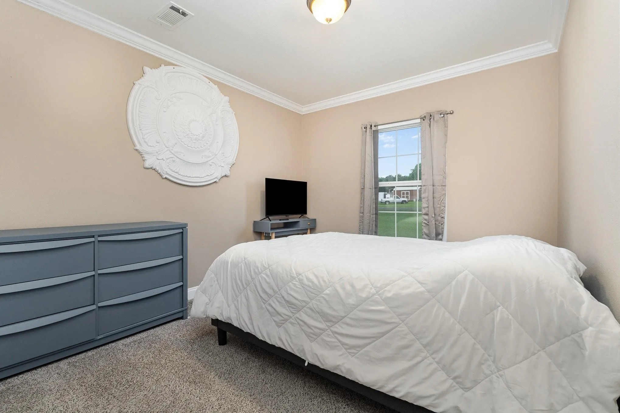 Bedroom featuring neutral tone walls, white crown molding, and carpeted flooring