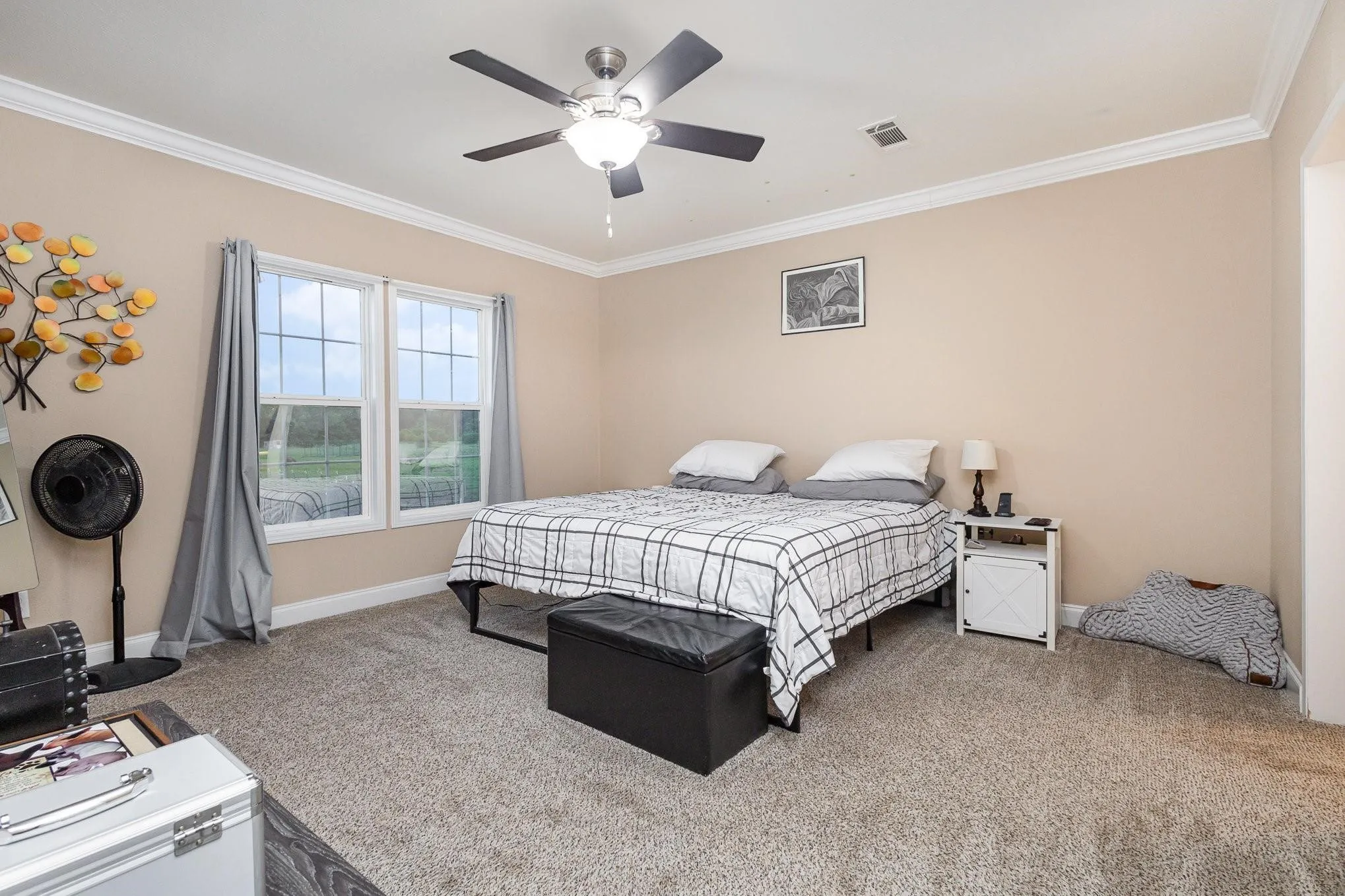 Bedroom featuring two windows, crown molding, a ceiling fan, and carpet flooring