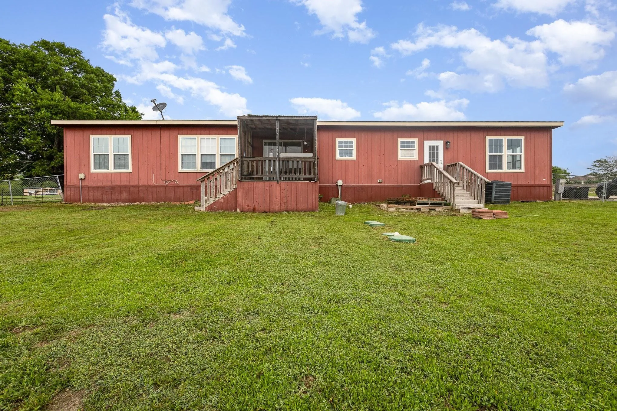 Expansive green lawn bordering the rear exterior of the residence, featuring red siding and multiple white-framed windows