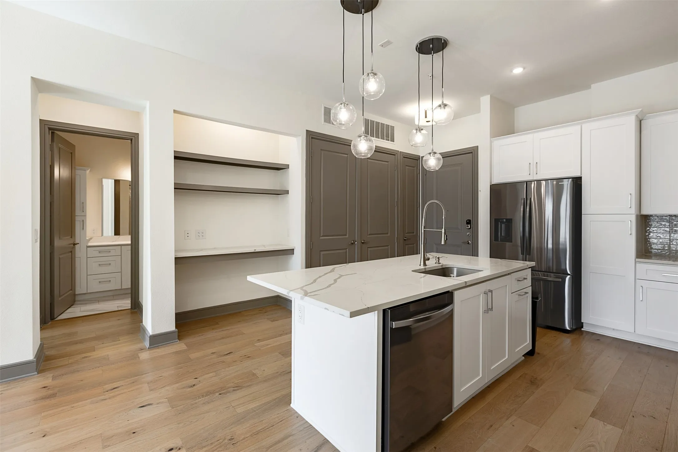 Open-concept kitchen featuring a quartz island with an undermount sink and contemporary pendant lighting