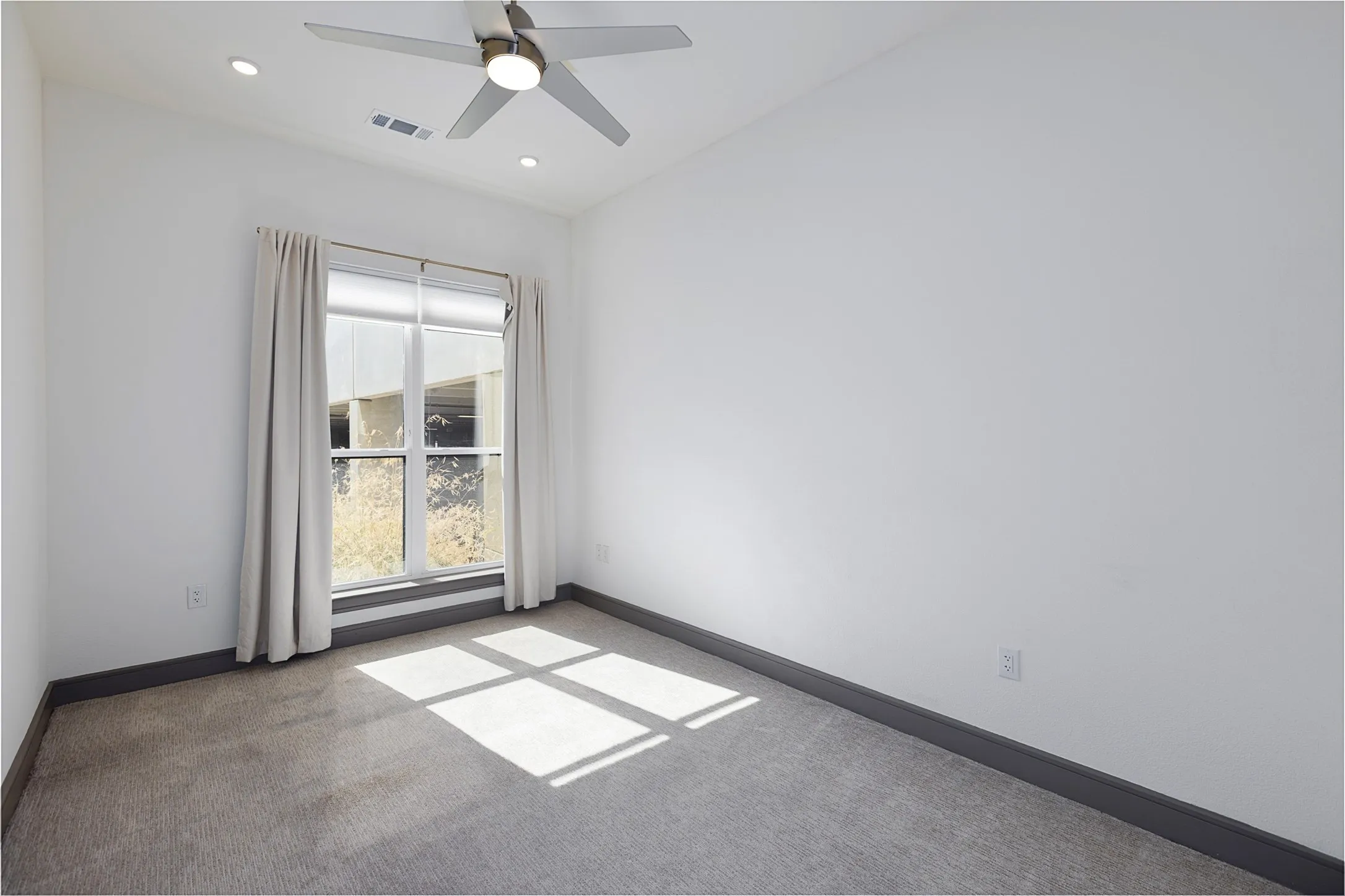 Carpeted room with a large window, recessed lighting, and a ceiling fan