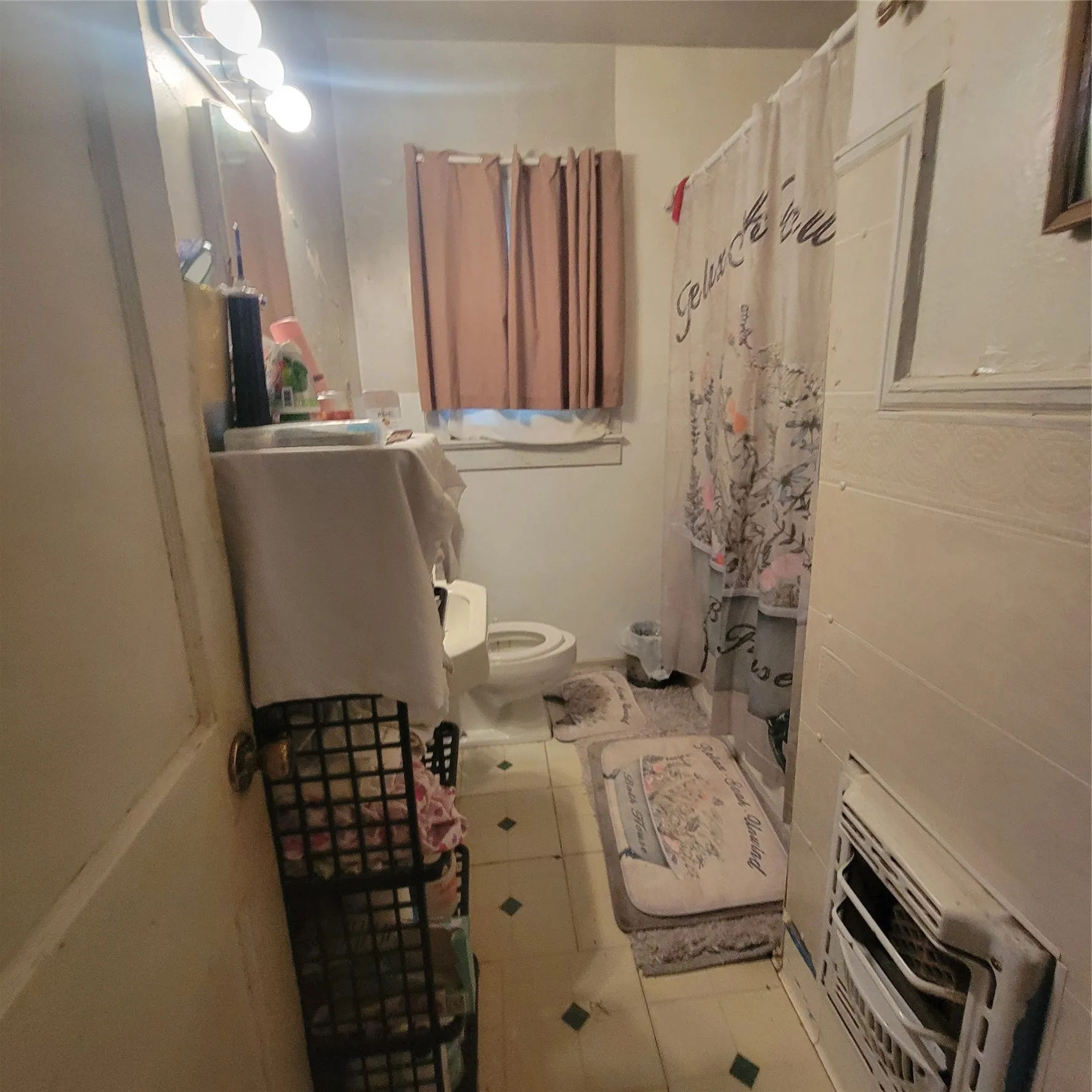 Bathroom featuring a vanity with an integrated sink, a toilet, and a window with privacy curtains
