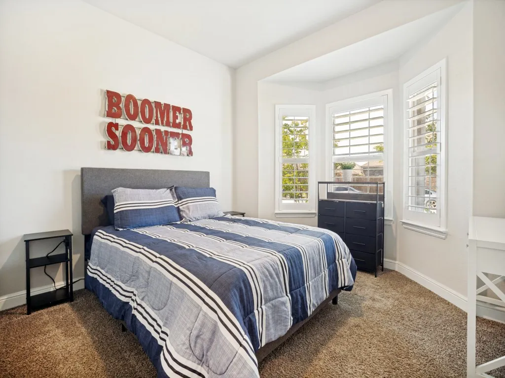 Bay window with plantation shutters, neutral wall color, and carpeted flooring