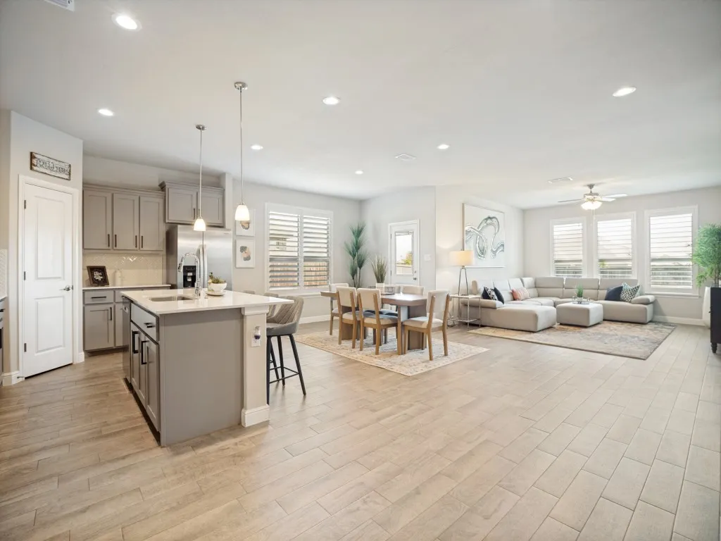 Open-concept living area featuring wood-finish flooring, recessed lighting, and a modern kitchen island with pendant lighting