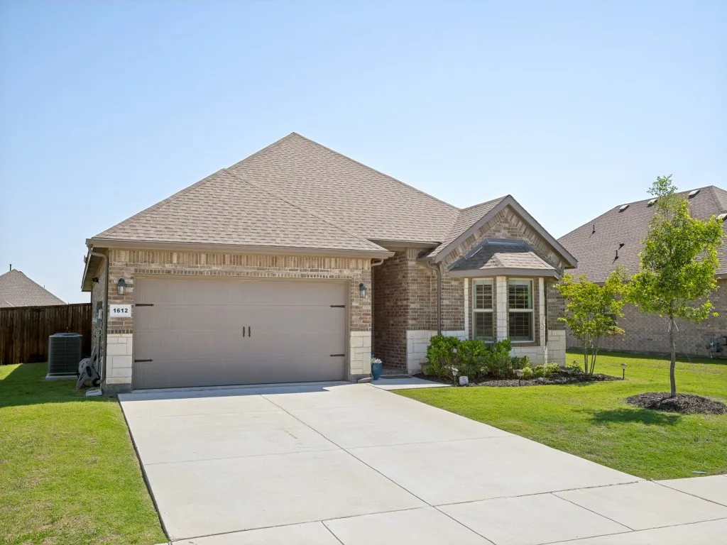 Brick and stone facade featuring a bay window, a two-car garage, and a concrete driveway
