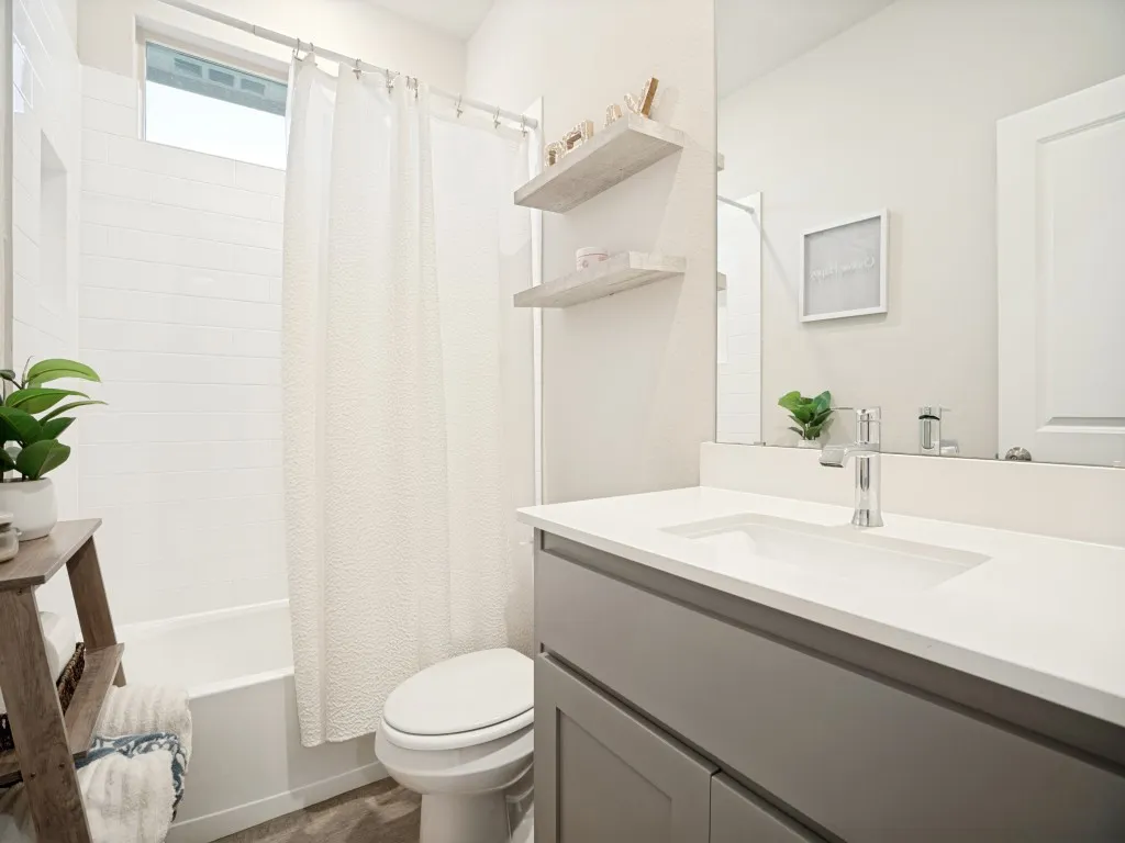 Bathroom featuring a white subway tile tub surround, transom window, grey vanity with an integrated sink, polished chrome faucet, and wood-finish flooring