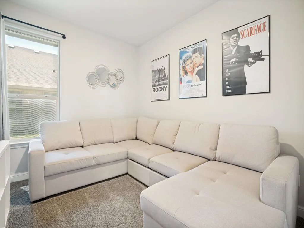 Carpeted room with a window featuring a dark curtain rod, white walls, and a built-in white shelving unit