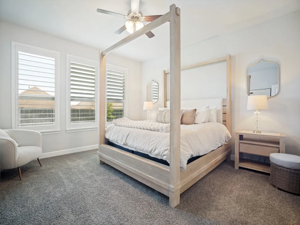 Carpeted room featuring multiple windows with plantation shutters, a ceiling fan, and light-toned walls