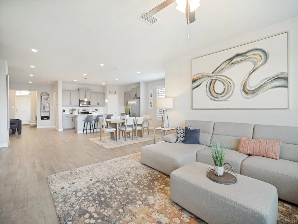 Open-concept living space featuring wood-finish flooring, recessed lighting, a ceiling fan, a kitchen island with seating, and stainless steel appliances