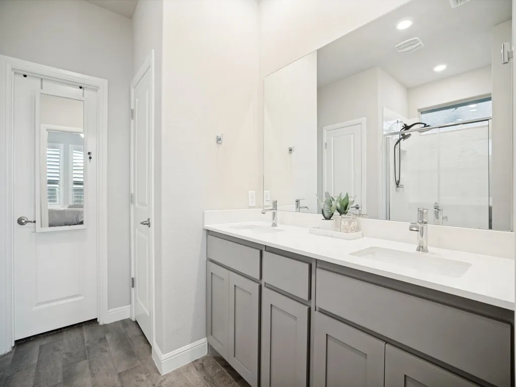 Bathroom featuring a dual vanity with undermount sinks, light gray cabinetry, and a large mirror
