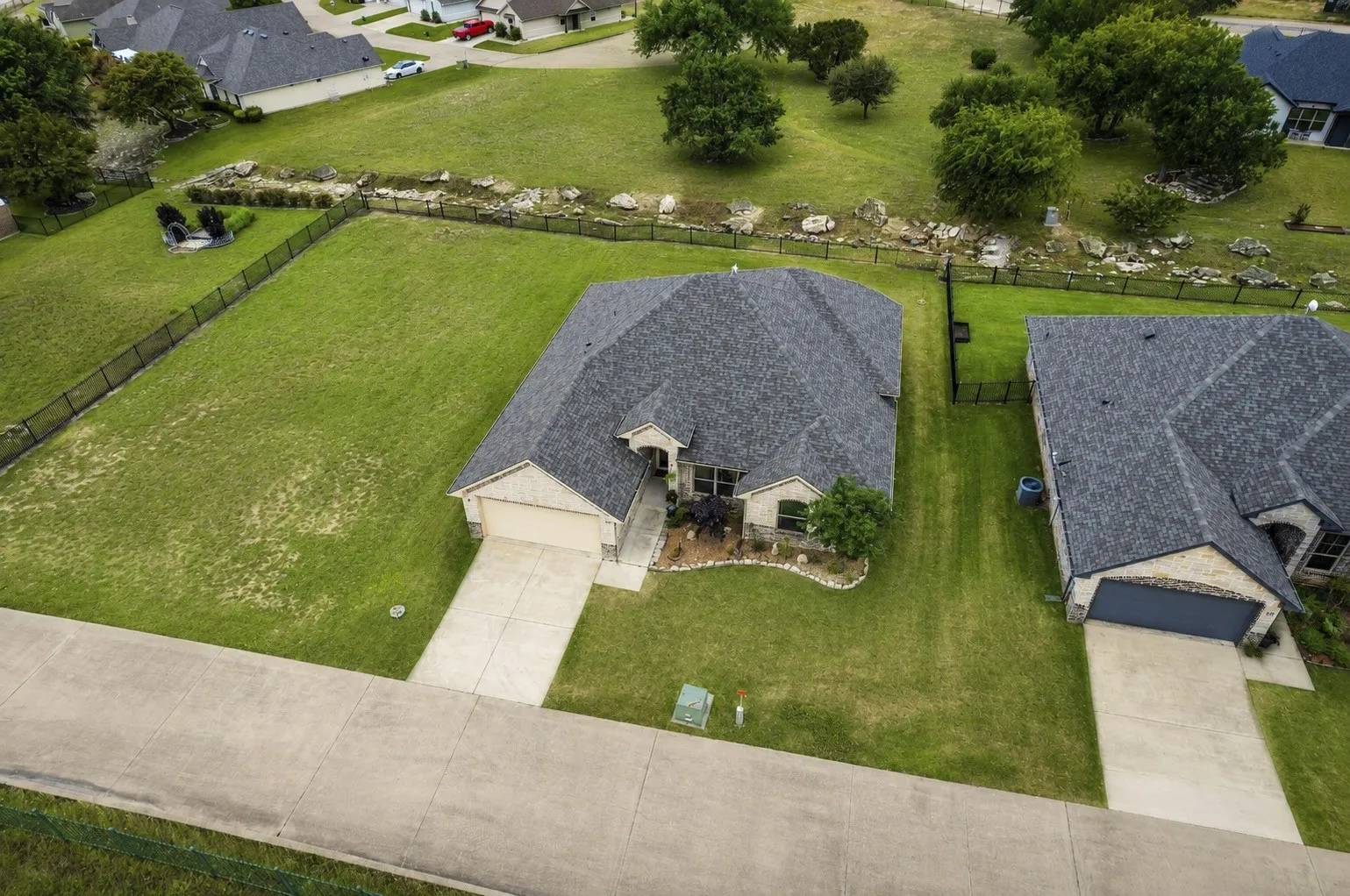 Aerial view highlighting the home's setting on a spacious lot with open green space nearby.