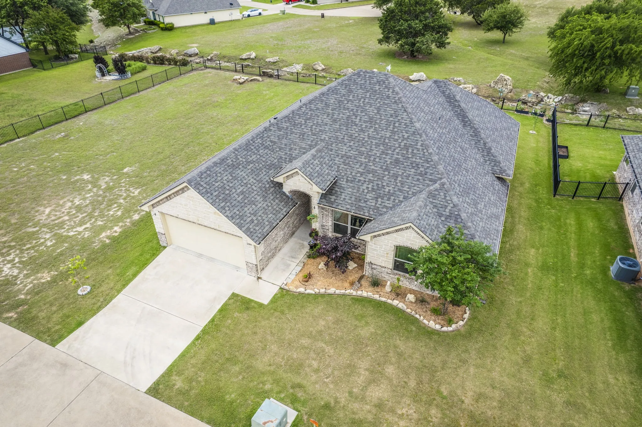 Aerial view showcasing the home's roofline, driveway, and backyard space.