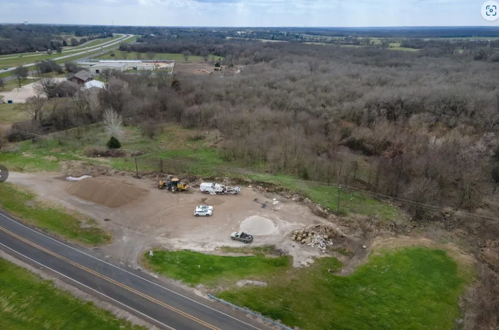 Expansive parcel featuring frontage on a paved road, a cleared building site, and surrounding natural woodlands