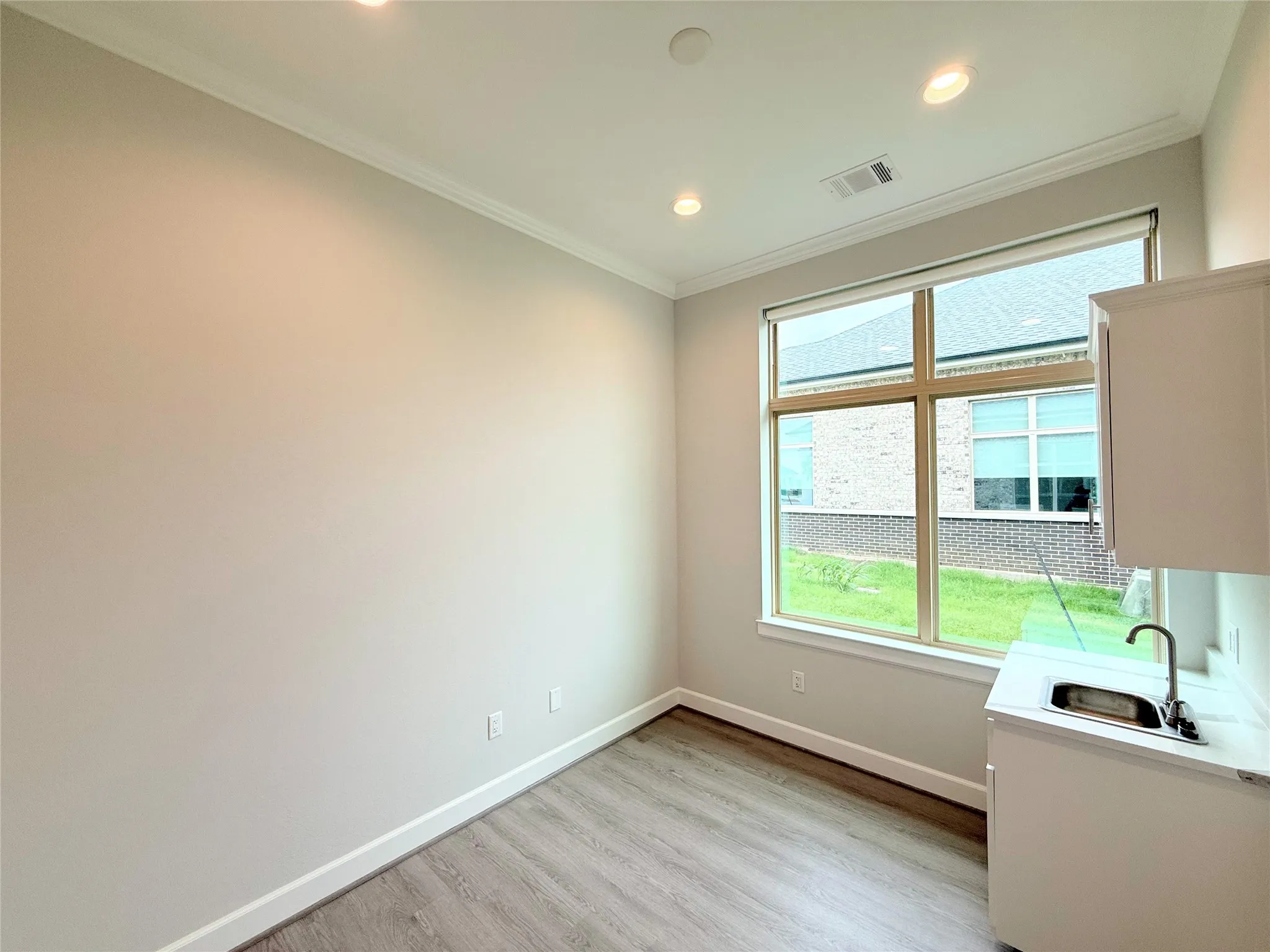 Versatile room featuring a large window, recessed lighting, wood-finish flooring, and crown molding