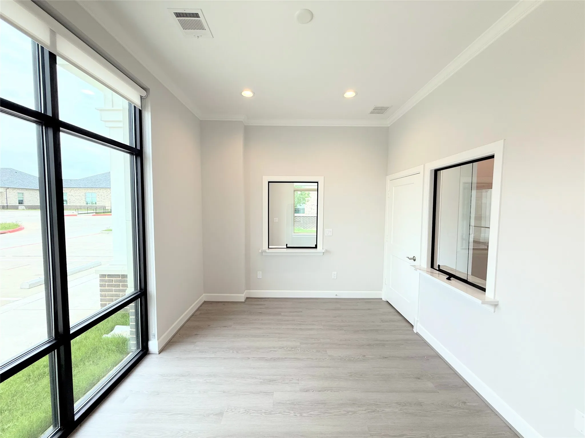 Spacious interior with expansive floor-to-ceiling windows, wood-finish flooring, recessed lighting, crown molding, and white interior doors