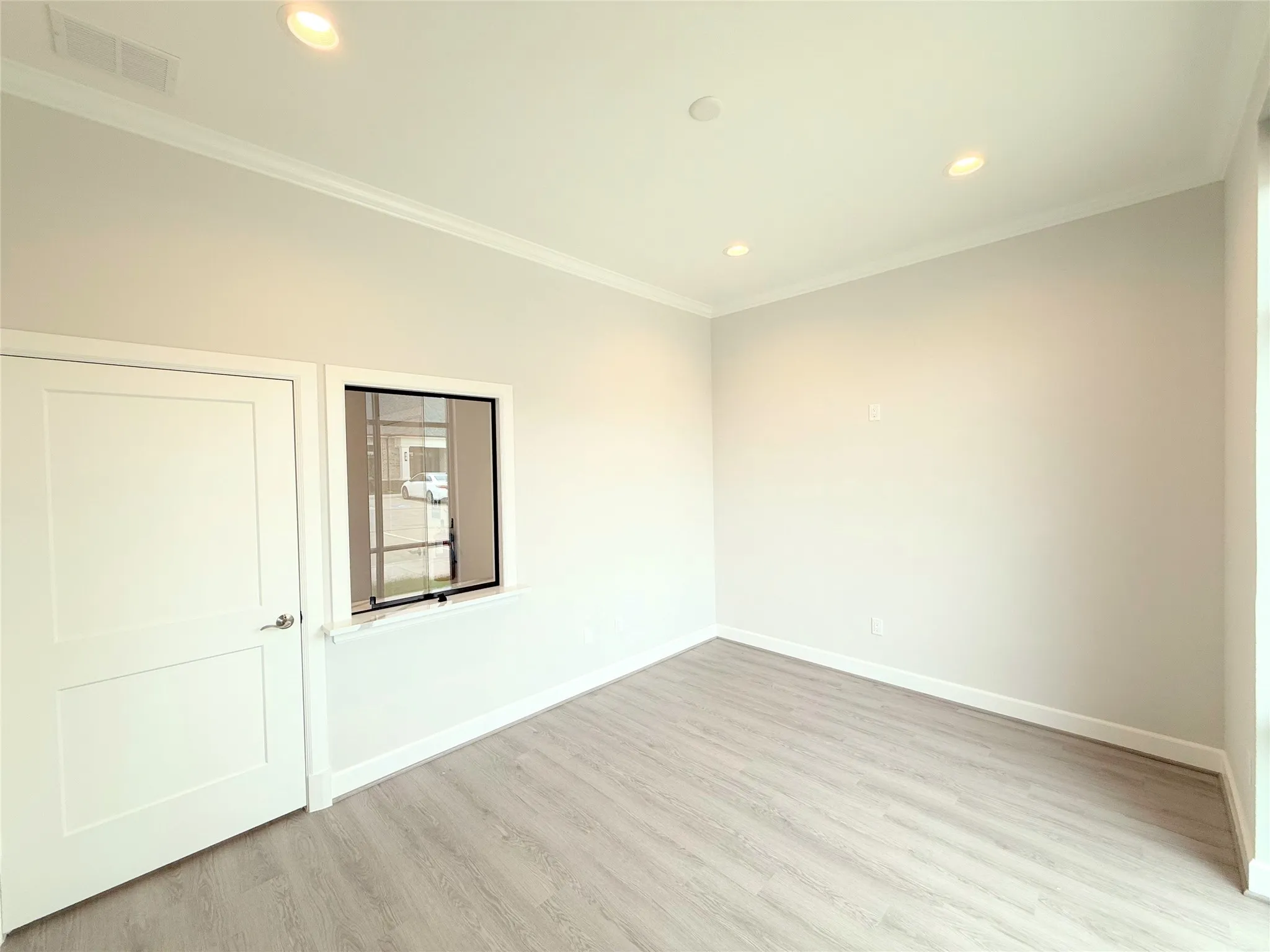 Room featuring wood-finish flooring, recessed lighting, crown molding, and a two-panel interior door
