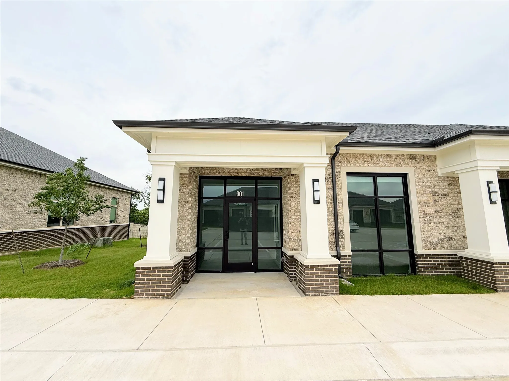 Modern commercial entrance featuring dark-framed glass doors and transom window