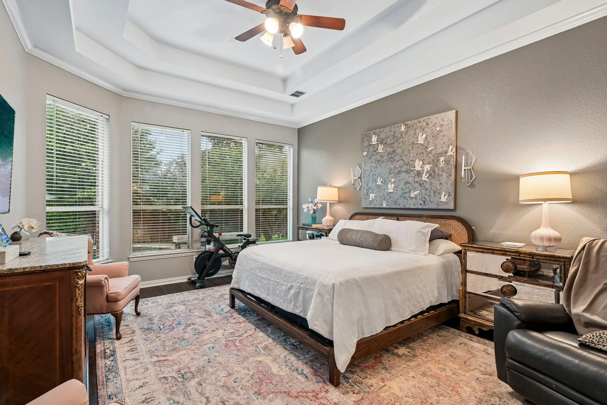 Spacious room featuring multiple large windows, a tray ceiling, and a ceiling fan with light fixture