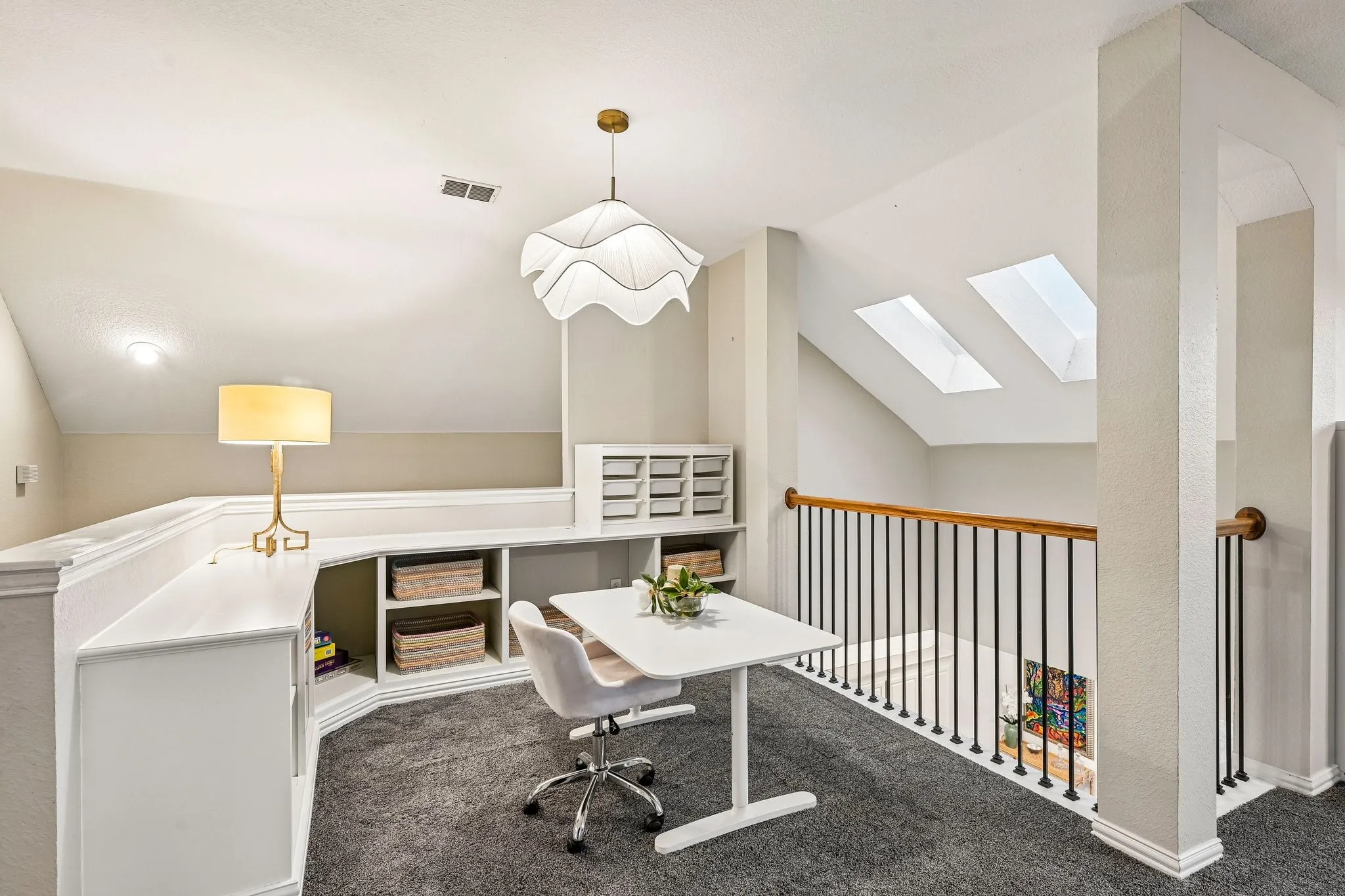 Craft loft area featuring built-in shelving, a contemporary pendant light fixture, and two skylights
