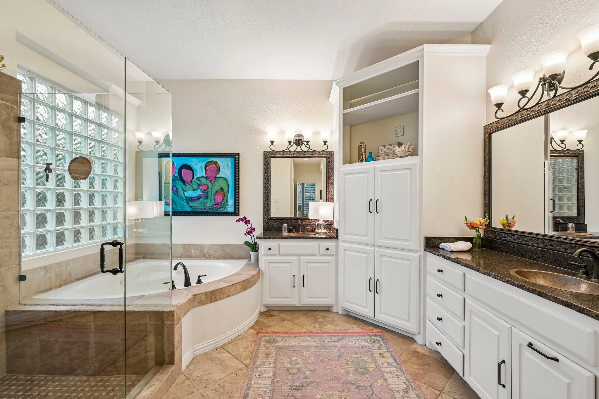 Bathroom featuring a glass-enclosed shower, a built-in tub with tile surround, dual vanity areas with dark countertops, white cabinetry, and a tall built-in storage unit