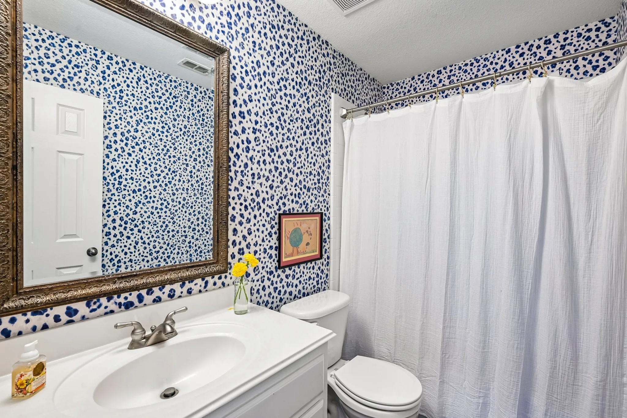 Bathroom featuring a white vanity with an integrated sink, a framed mirror, and a toilet