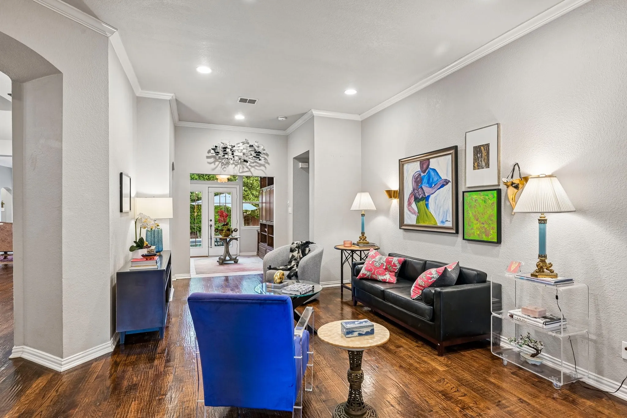 Living area featuring rich wood-finish flooring, recessed lighting, crown molding, and an arched entryway