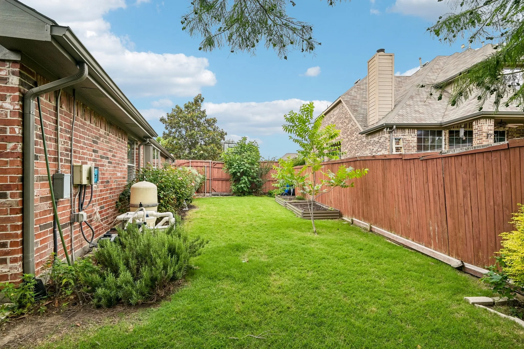 Manicured lawn with a wood privacy fence, brick exterior, and a visible rain gutter system
