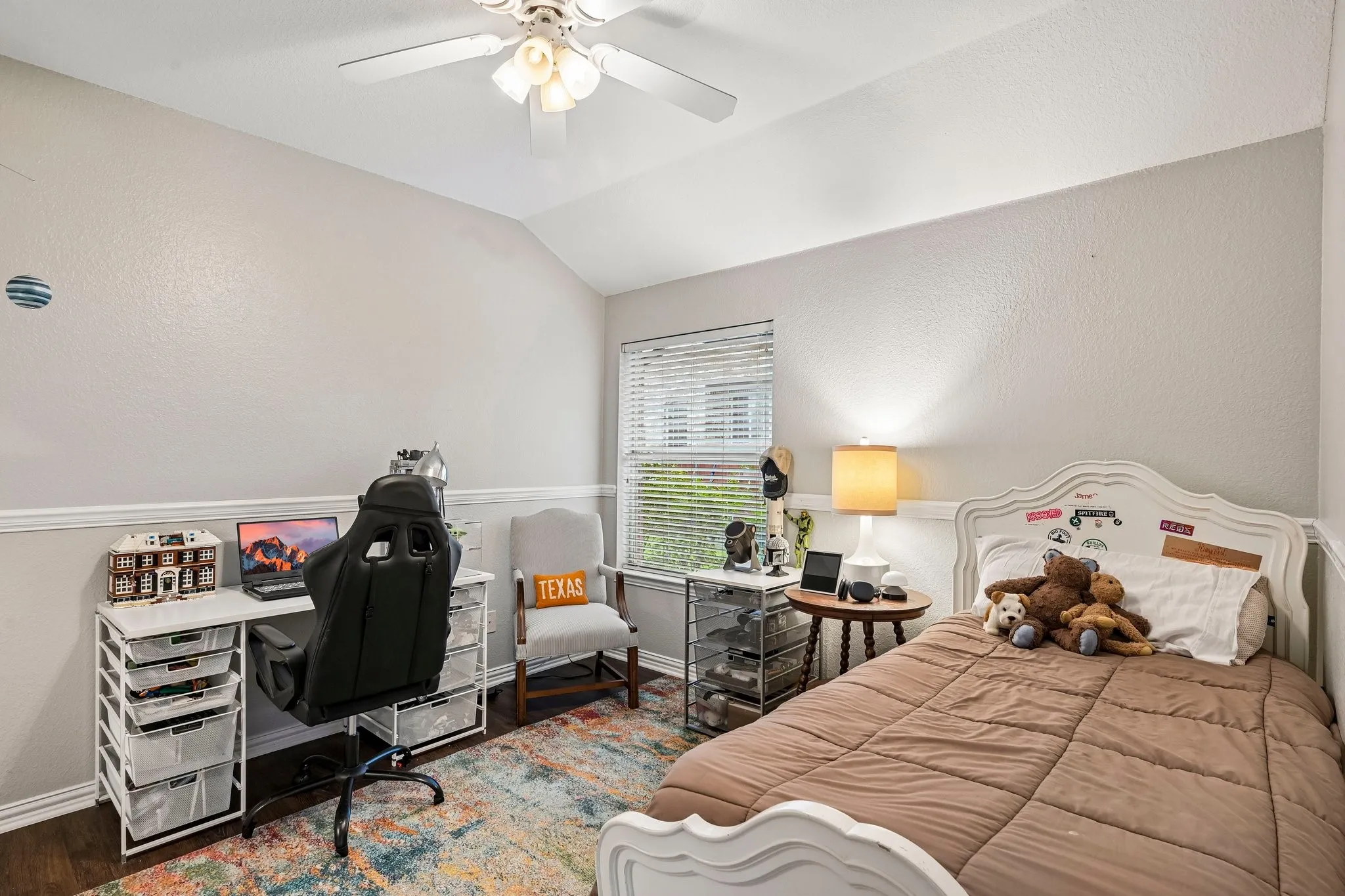 Vaulted ceiling bedroom with wood-finish flooring, white wall trim, and a window featuring horizontal blinds