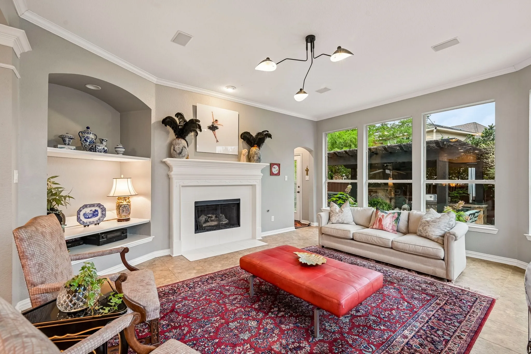 Living area featuring a fireplace with a white mantel, built-in shelving, crown molding, and large windows