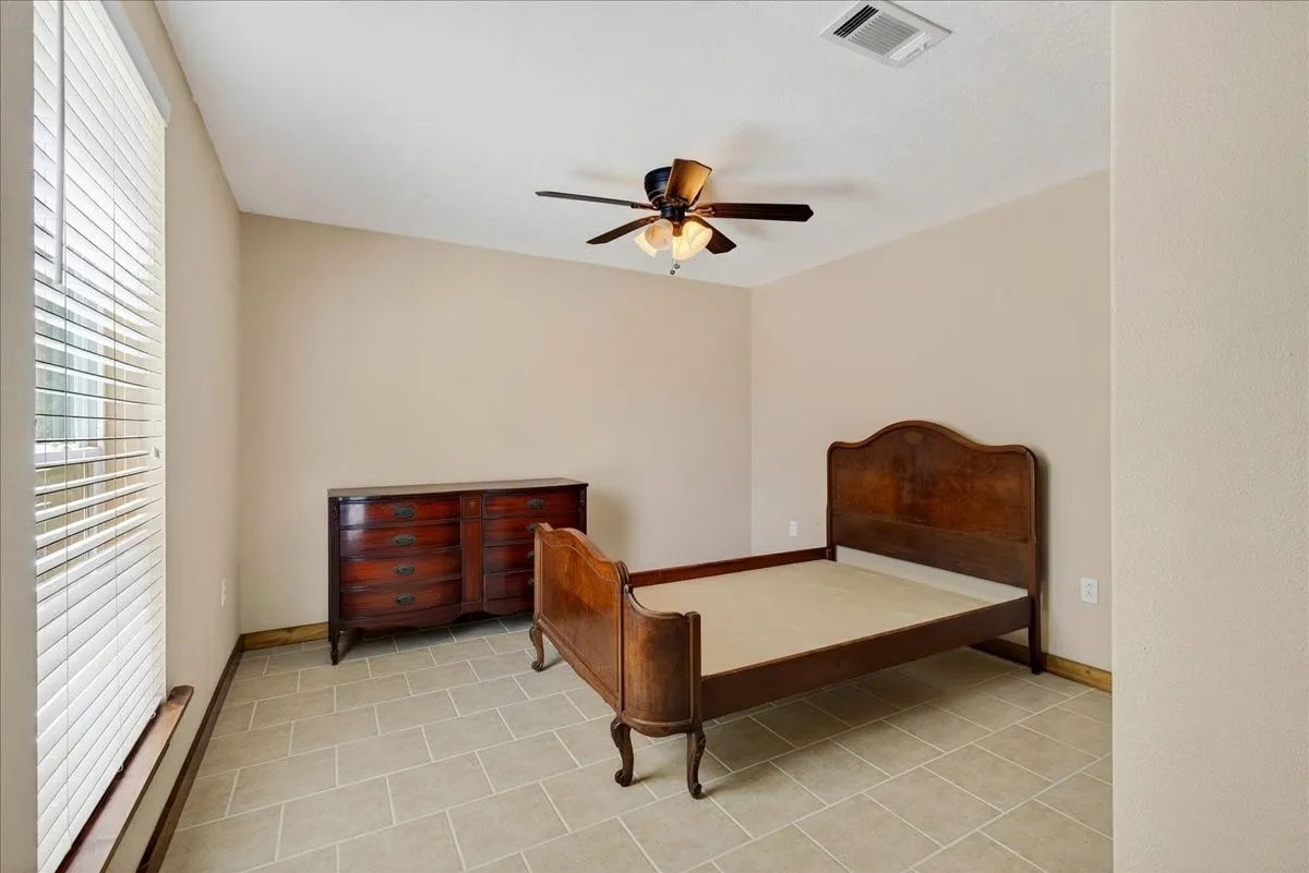6th Bedroom in Basement featuring neutral-toned walls, tile flooring, a window with horizontal blinds, and a ceiling fan with integrated lighting