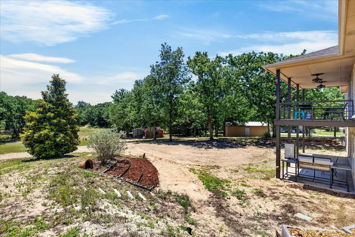 Expansive outdoor area featuring a two-story covered patio, mature trees, and a detached outbuilding