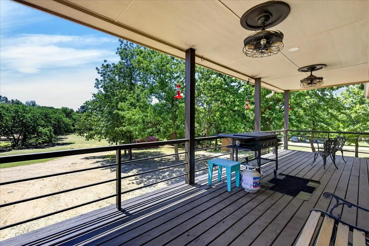 Spacious outdoor deck and back porch balcony featuring a black metal railing overlooking a tree-lined serene landscape.