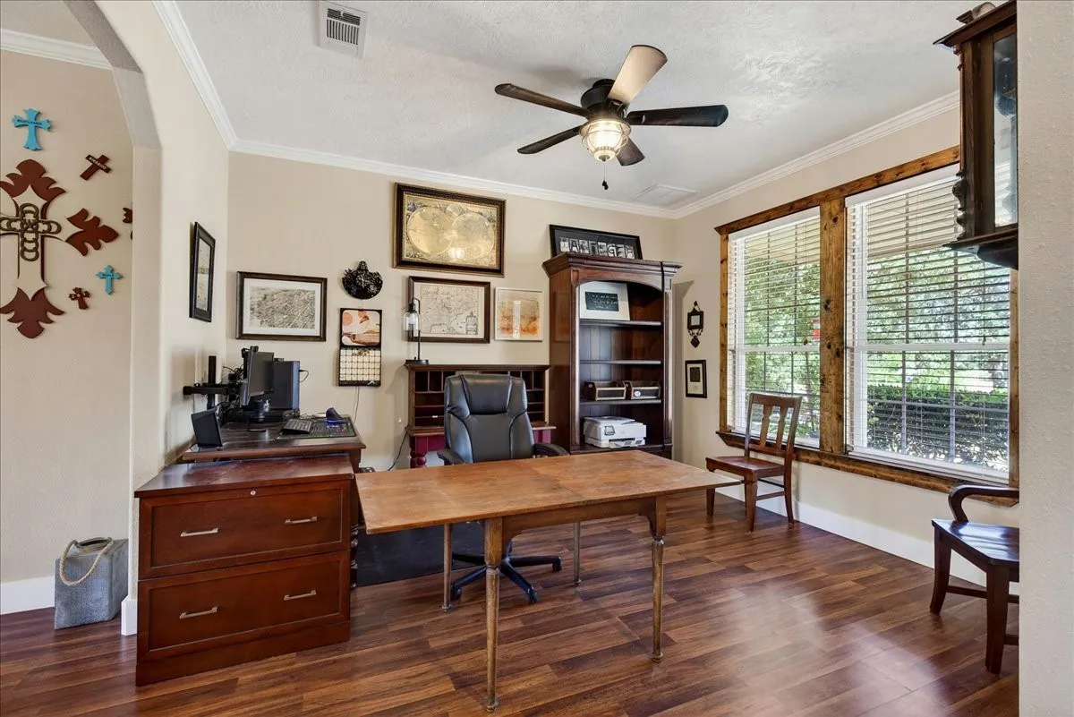 Flex space/office featuring wood-finish flooring, two large windows with natural wood trim, and crown molding