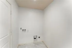 Utility space featuring white walls and marble-look tile flooring