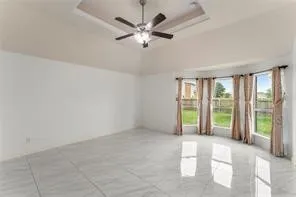 Spacious interior featuring a coffered ceiling, modern ceiling fan, large bay windows, and tiled flooring