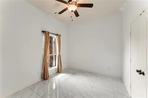 Vaulted ceiling room featuring large format tile flooring, a window with curtain rod, a ceiling fan with integrated lighting, and a paneled door with dark hardware