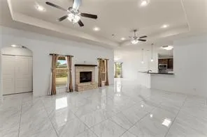 Spacious interior featuring large format tile flooring, a stone-clad fireplace, and recessed lighting