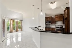 Kitchen with dark wood cabinetry, stainless steel appliances, and a tiled backsplash
