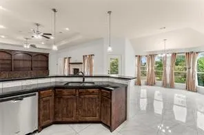 Kitchen featuring dark wood cabinetry, black countertops, and a stainless steel dishwasher