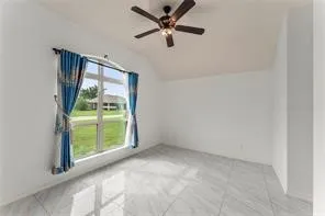 Spacious room featuring a large window, light-toned tile flooring, white walls, and a ceiling fan