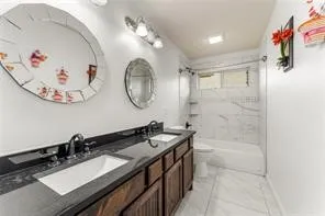 Double vanity with dark wood-finish cabinetry and undermount sinks