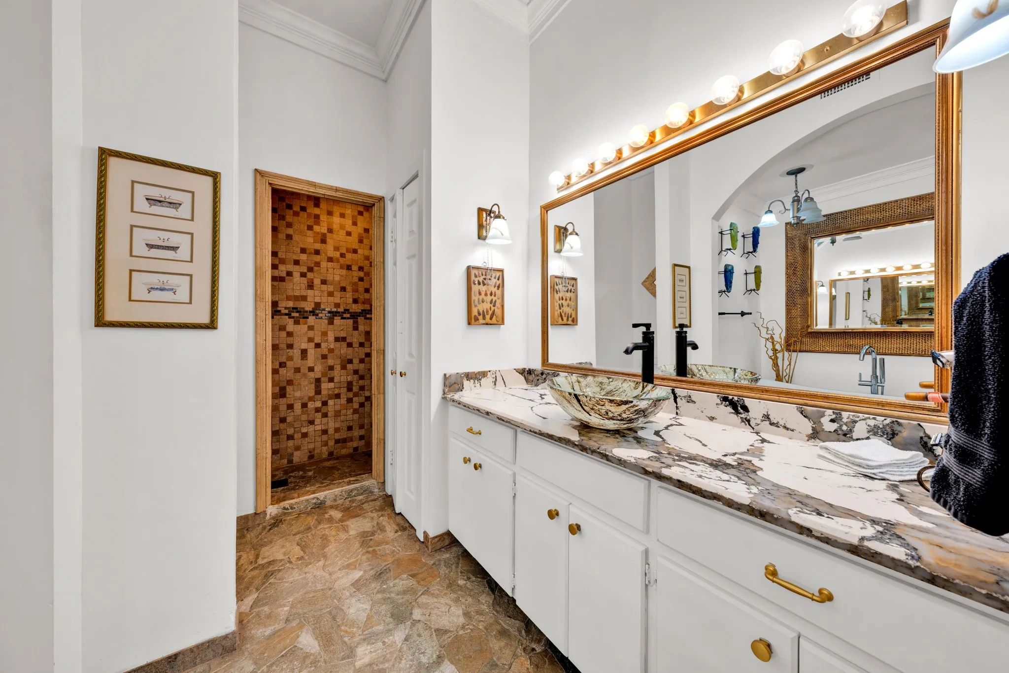 Custom tile shower, spacious vanity with intricate countertop, vessel sink, and large wall-mounted mirror