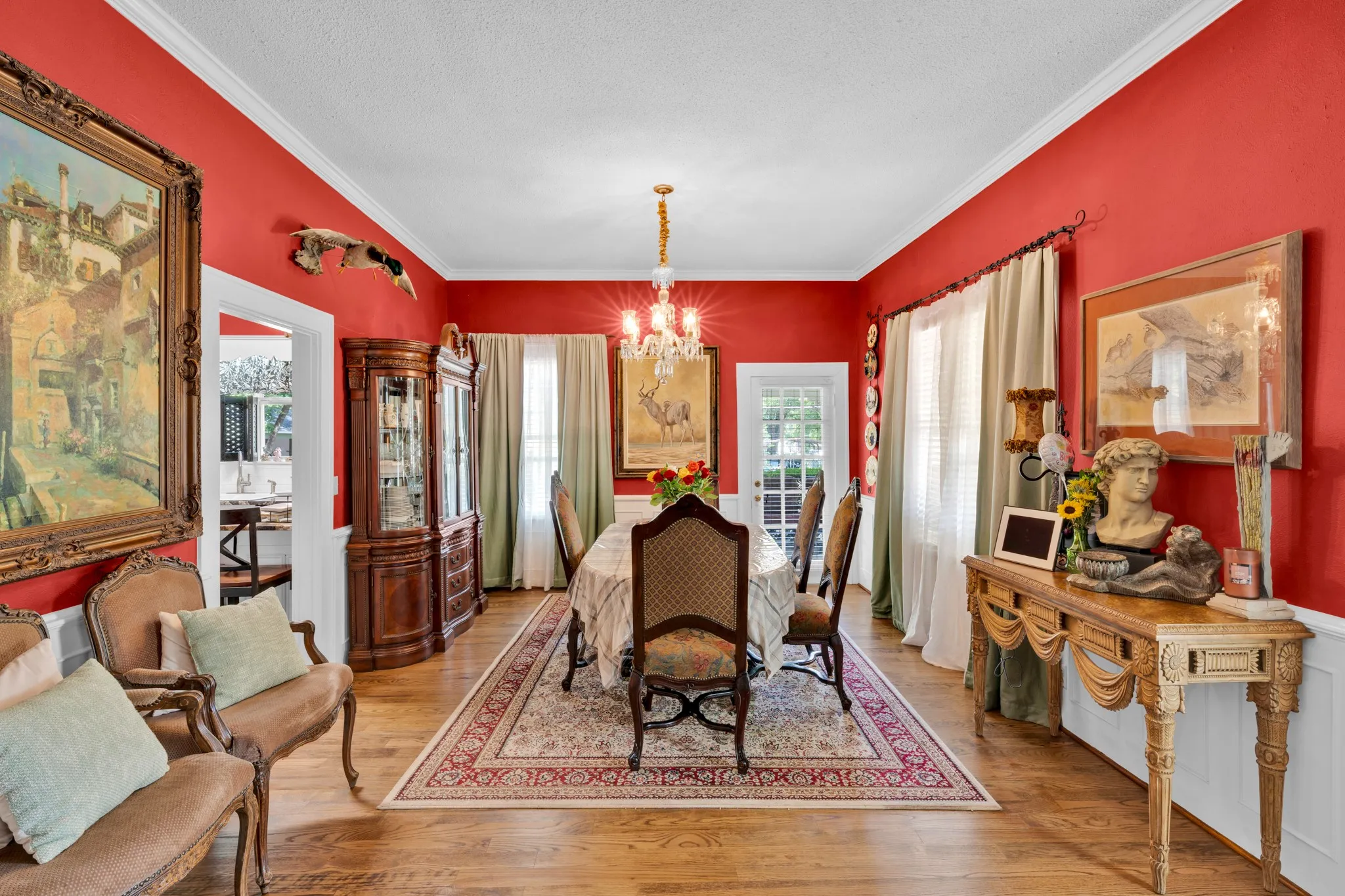Hardwood flooring, crown molding, white wainscoting, and a glass-paneled door
