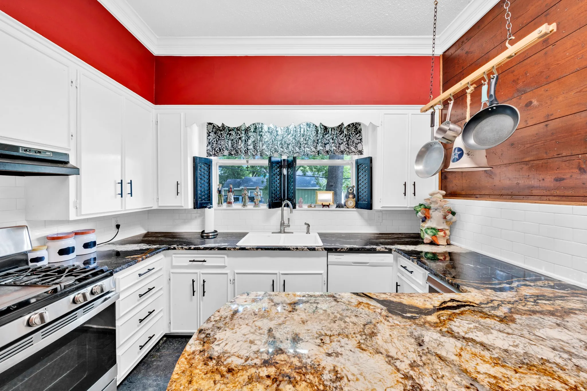 White cabinetry with matte black hardware, stainless steel gas range, built-in dishwasher, patterned countertops, and a subway tile backsplash