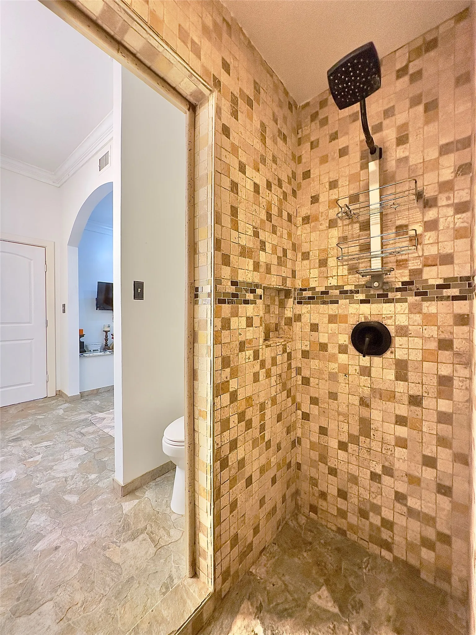 Tiled shower enclosure with a dark-finish shower head and a recessed niche