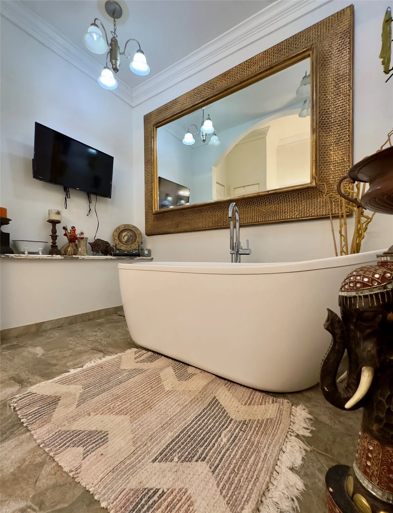 Freestanding soaking tub with a floor-mounted faucet, complemented by a large framed mirror